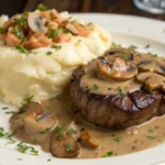 Grilled steak with mushroom gravy served alongside mashed potatoes garnished with parsley.